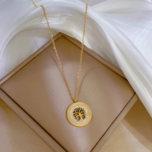Golden Tree of Life necklace with sparkling crystals on a beige jewelry box with silk