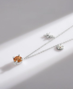 Detail of silver necklace with orange zircon pendant and delicate dragonfly element