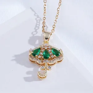 Close-up of gold umbrella pendant necklace with green zircons and diamond details