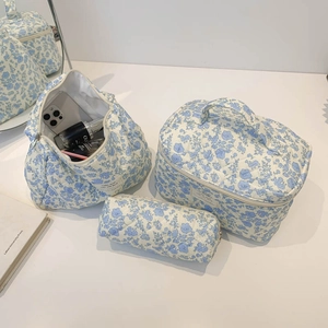 Three-piece quilted cotton floral cosmetic bag set with blue begonia pattern on a white table