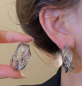 Close-up of vintage hollow twisted earrings in polished silver finish on ear
