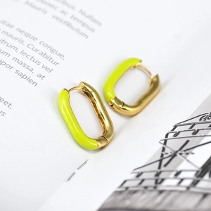 French style gold-plated oval hoop earrings with bright green enamel on a magazine background