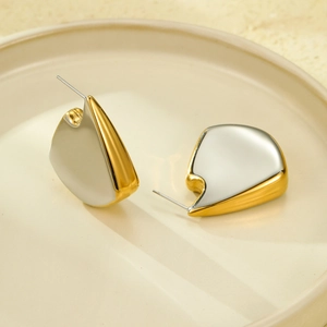 Irregular fin-shaped mixed-color stud earrings in gold and white on a ceramic tray