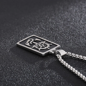 Détail du pendentif rectangulaire noir avec gouvernail en argent sur une chaîne de boîte