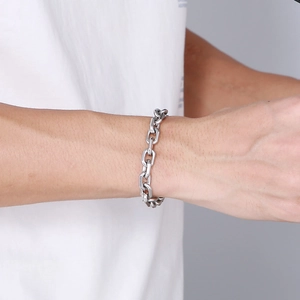 Macro shot of silver stainless steel curb chain bracelet worn on a male wrist