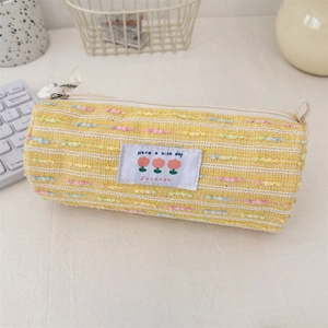 Primer plano del estuche tejido amarillo con bordado de tulipa y cremallera metálica