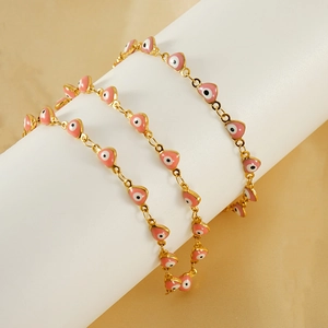 Detailed view of pink heart-shaped evil eye enamel charms on a gold stainless steel chain
