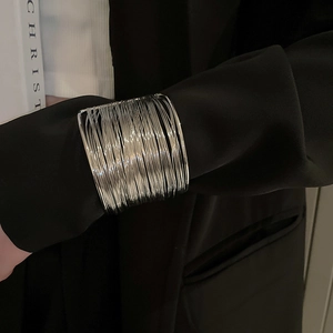 Macro view of wide silver multi-layer wire wrapped cuff bracelet on black suit sleeve