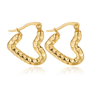 Detail of golden heart-shaped earrings with irregular hammered texture on white background