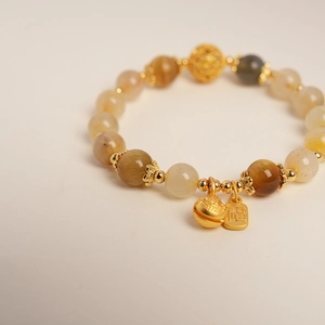 Détail du bracelet en perles de citrine avec pendentif Fu doré et clochette