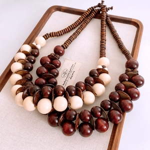 Primo piano della collana etnica con perle in legno marrone e crema su vassoio