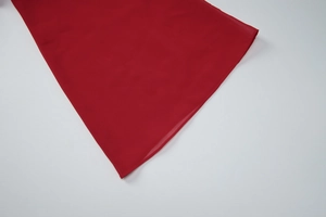 Gros plan détaillé du tissu rouge avec coutures soignées sur robe à manches évasées