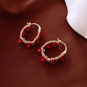 Détail de boucles d'oreilles créoles dorées en U avec roses rouges et zircons blancs
