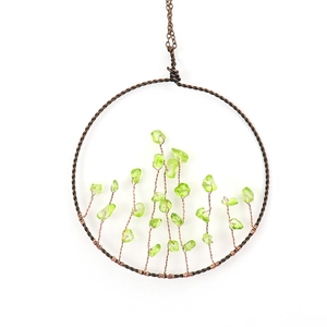 Close-up of tree of life pendant with copper wire and green crystal stones