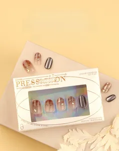 Detailed view of amber gold-foil marble and red mirror press-on nails with small rhinestones
