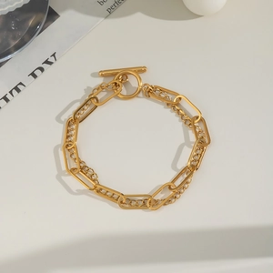 Close-up of golden double-layer chain bracelet with designer OT toggle clasp detail