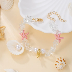 Detail of beaded bracelet with starfish, seashell, and natural stones on shell tray