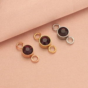 Three-color birthstone connectors in rose gold, gold, and silver on pink fabric