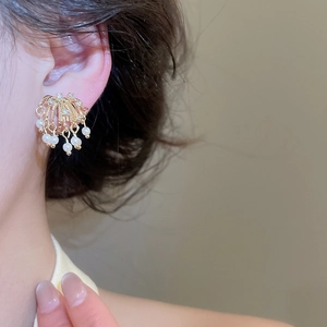 Close-up of 18k gold plated firework earrings with pearls and zircons on ear.