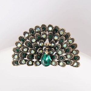 Detailed close-up of a peacock brooch with green crystals and sparkling rhinestones