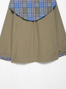 Close-up of khaki woven jacket featuring blue and brown plaid patchwork on the collar and cuff