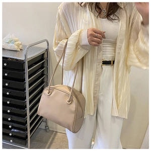 Close-up of beige leather tote bag with semi-circular design worn by a model