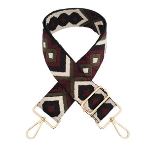 Detail of red and green diamond pattern woven bag strap with golden metal clasps
