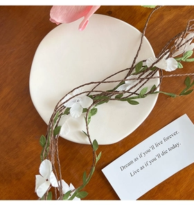 Detail of white floral headband with realistic blossoms on rustic woven branch base