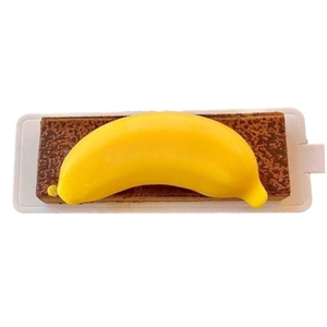 Close-up of yellow banana shaped mousse cake on a chocolate brownie base with white tray