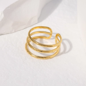 Macro shot of gold triple-layered open ring with hammered texture on white background