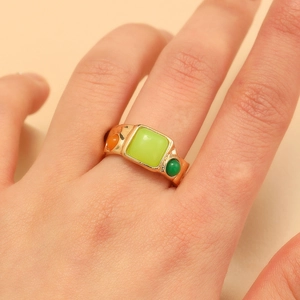Primer plano de anillo vintage dorado con gema verde cuadrada y detalles de colores
