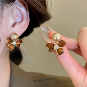 Detail of 18k gold plated flower stud earrings with pearl and sparkling zircon accents