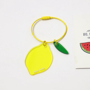 Macro shot of a yellow acrylic lemon keychain with a leaf charm and wire ring loop