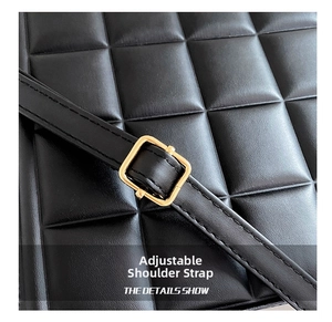 Detail view of the black quilted shoulder bag featuring a gold metal adjustment buckle