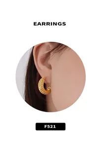 Macro shot of thick golden hoop earring with textured hammer finish on model