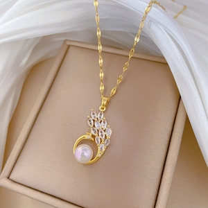 Detailed shot of gold peacock pendant with zircon gems and large white pearl on silk