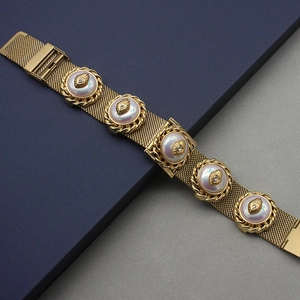 Detailed macro view of vintage gold mesh bracelet with mother of pearl and heart charms