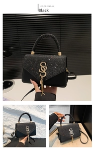 Detail of black sequin crossbody bag with golden tassel buckle and metal chain strap