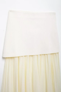 Detailed view of the pleated beige tulle hem and white knit fabric contrast on the skirt