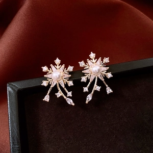 Gros plan détaillé de boucles d'oreilles fleur dorées avec perle et glands en zircon