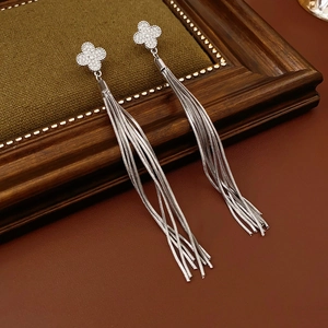 Macro detail of silver four-leaf clover earrings with sparkling tassel chains and diamonds