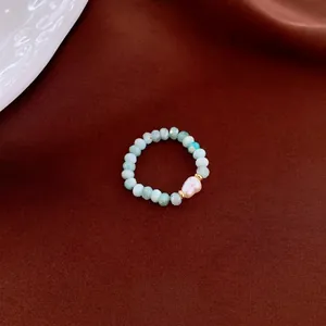 Handmade beaded ring featuring green amazonite stones and a white baroque pearl on fabric
