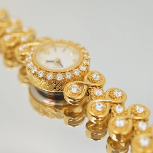 Macro shot of luxury gold vintage watch with diamond-encrusted bezel and S-shaped bracelet