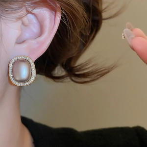 Close-up of vintage oval earring featuring a cat-eye stone and crystal-paved border
