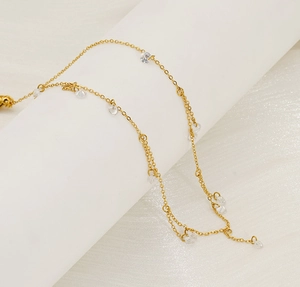 Detail of elegant gold chain necklace featuring sparkling round zircon stones on a white stand