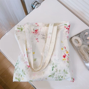 Macro shot of cotton floral tote bag with watercolor blossoms and stitched brand label
