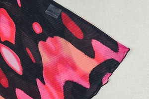 Detail of printed mesh fabric with red abstract patterns and stitching quality