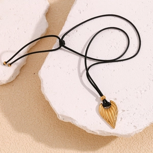 18K gold plated heart wing pendant with black leather cord on minimalist stone base