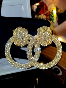 Close-up of sparkling gold hoop earrings fully paved with crystals for a glamorous look