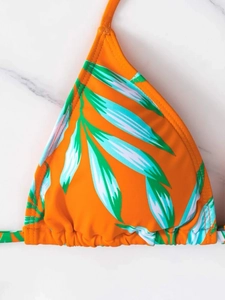Detail of orange halter bikini top featuring green tropical palm leaf print and ruched design